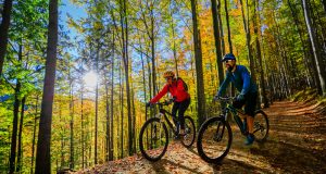 Cycling,Woman,And,Man,Riding,On,Bikes,At,Sunset,Mountains